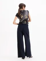 Pantalón sastre color negro de corte recto y tiro alto, confeccionado en mezcla de viscosa y elastano. Presenta bolsillos laterales, presillas para cinto y un delicado vivo decorativo a lo largo de los laterales.