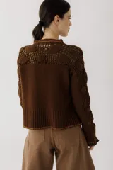 Saco de punto color beige, con diseño de calados en la parte superior y mangas, cierre frontal con botones y cuello redondo.