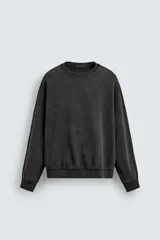 Sudadera de corte relaxed fit confeccionada en tejido de algodón con interior de rizo. Presenta cuello redondo, manga larga y acabados en rib, con un acabado de efecto lavado que le otorga una apariencia única.