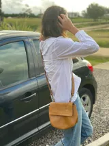 Bandolera pequeña de cuero color marrón claro, con correa larga ajustable y cierre con solapa.