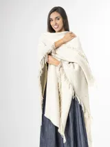 Ruana off white de tejido texturado con detalles sutiles de hilos multicolor y terminación de flecos en los bordes.