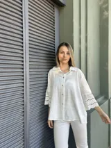 Camisa blanca de mangas 3/4 con detalles de encaje en las mangas.