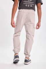Pantalón tipo cargo jogger color gris claro, con cintura elástica ajustable mediante cordón, bolsillos laterales tipo cargo y puños elásticos en los tobillos.