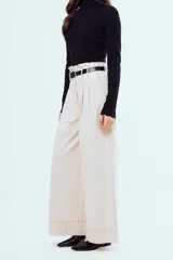 Pantalón marrón de corte ancho y talle alto, con pinzas frontales y bolsillos laterales.