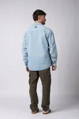 Chaqueta de denim celeste de corte relajado, con cuello clásico, cierre frontal con botones metálicos y un bolsillo aplicado en el pecho.