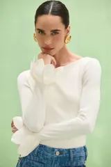 Blusa negra de manga larga, corte ajustado y escote bote. Cuenta con detalle de lazos o nudos en los puños.