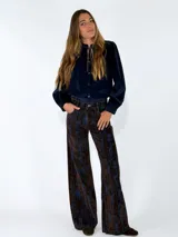 Pantalon de corte recto y tiro alto, confeccionado en tela con textura tipo pana o denim con un estampado abstracto en tonos marrones y azules.