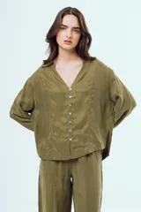 Camisa negra de manga larga con cuello en V, cierre frontal de botones y costuras decorativas en contraste de color blanco.