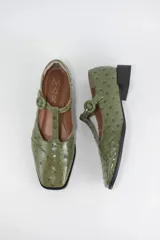 Zapatos estilo Mary Jane de cuero con acabado acharolado y textura efecto croco en color marrón oscuro. Presentan punta cuadrada, cierre con tira en el empeine y taco cuadrado bajo.