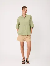 Camisa de manga corta celeste, confeccionada en mezcla de algodón y lino, con cuello camisero y cierre frontal de botones.