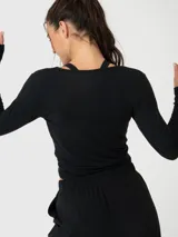 Polera de manga larga color negro, confeccionada en modal, con diseño de nudo frontal y corte cropped.