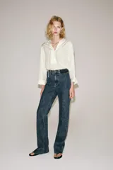 Camisa blanca ZARA Woman Collection de 100% seda, con escote en V ajustable con cordones entrelazados y manga larga con puños rectos.