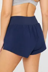 Short deportivo de tiro alto color azul marino, con diseño de corte curvo en los laterales y logo reflectante en la parte inferior. Cuenta con cintura elástica ancha y calza interior incorporada.