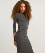 Vestido midi gris confeccionado en rib de algodón y elastano. Posee cuello redondo, manga larga y drapeado lateral con abertura en la parte inferior.