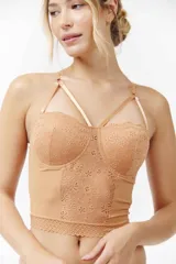 Bustier color beige, con copas de encaje floral y tirantes finos ajustables que forman un diseño cruzado en el escote. El cuerpo es de tela lisa con un borde inferior de encaje con patrón geométrico.