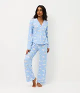 Pijama largo estilo americano de poliéster, compuesto por una camisa de manga larga con cuello solapa y cierre frontal de botones, y un pantalón largo de corte recto. Presenta un estampado integral del personaje Cinnamoroll sobre un fondo celeste.