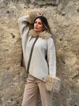 Saco de punto acanalado en color beige, con cierre frontal y detalles de piel sintética en el cuello y los puños.