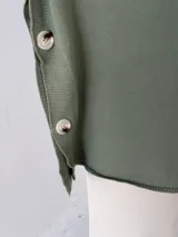 Polerón de punto color verde, con cuello alto, mangas largas con puños acanalados y detalle de botones laterales en el ruedo.
