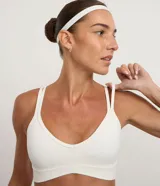 Top deportivo blanco de microfibra, con escote en V y tirantes finos que se cruzan en la espalda en forma de X.