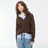Sweater de punto color marrón, con cuello en V y mangas largas con puños acanalados. Presenta un diseño de corte holgado y tejido liso.