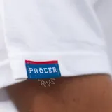 Remera blanca de algodón con cuello redondo y manga corta. Estampado pequeño en el pecho de un jugador de fútbol pateando la pelota.