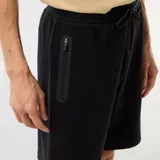 Bermuda de punto piqué estilo deportivo color negro, con cintura elástica ajustable mediante cordón y bolsillos laterales con cierre.