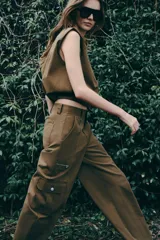 Pantalón de tiro alto con diseño tipo cargo, pernera holgada que se estrecha hacia el tobillo, bolsillos laterales con cierre y bolsillos de plastrón con solapa.