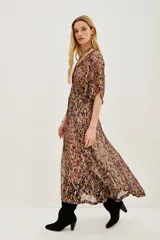 Vestido largo con estampado de hojas en tonos otoñales y metalizados, escote en V con botones frontales y mangas mariposa amplias. Presenta un lazo ajustable a la cintura y abertura frontal en la falda.