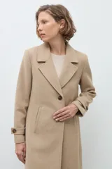 Tapado clásico de corte recto en color beige, con solapas, cierre frontal de botones y bolsillos laterales. Presenta un diseño minimalista y elegante.