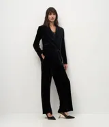 Blazer de terciopelo color negro con largo extendido, diseño cruzado con botones frontales, solapa clásica, bolsillos con tapa y mangas largas.