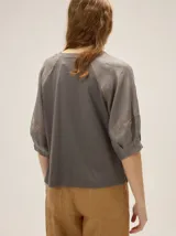 Remera de algodón con escote a la base y mangas raglán de broderie con costuras decorativas en color contrastante.