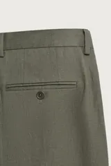 Pantalón de traje regular fit de lino color verde militar, con bolsillos laterales y bolsillos traseros de doble vivo con botón. Cierre frontal con cremallera y botón.