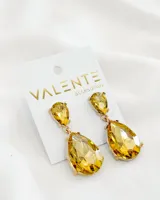 Aros colgantes dorados con dos cristales facetados en forma de lágrima color amarillo.