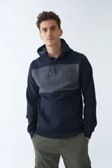 Buzo canguro de felpa azul marino y gris con capucha ajustable, bolsillo tipo canguro, mangas largas y logo en relieve.