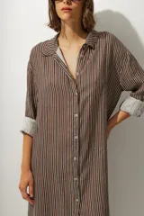 Vestido camisero midi de corte recto y holgado, con estampado de rayas verticales en tonos tierra, cuello camisero, cierre frontal de botones y mangas tres cuartos con puños vueltos.