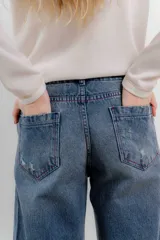 Pantalón de jean color naranja con tiro medio, diseño de pierna ancha y cinco bolsillos. Presenta costuras con pespuntes a contratono.