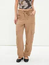Pantalon cargo color tostado con cintura elastizada y cordón ajustable. Presenta bolsillos laterales tipo cargo y costuras visibles a lo largo de las piernas.