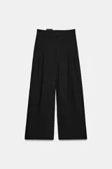 Pantalón de tiro medio color marrón, con pinzas en el delantero, perneras anchas de corte recto y trabillas para cinturón. Cuenta con bolsillos laterales y traseros, y cierre frontal con cremallera y botón.