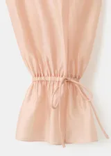Blusa de lyocell color rosado pálido, de diseño recto con escote en V, detalle de volantes en la solapa y manga larga con puños ajustables.