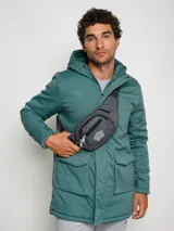 Parka larga gris con capucha, cierre frontal con cremallera y botones a presión, múltiples bolsillos y logo de Umbro en el pecho.