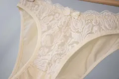 Bombacha de bikini tiro bajo/medio, color negro, confeccionada con tela que contiene fibra LYCRA® y frente de puntilla elastizada.