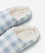 Pantufla cerrada para mujer con diseño a cuadros en tonos celeste y blanco, forro interno de corderito sintético y suela plana en tono celeste claro.