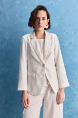 Blazer color beige claro, de corte clásico con solapa, cierre de un botón y bolsillos delanteros de vivo.