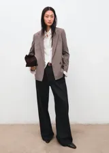 Blazer de corte recto y silueta estructurada, con cuello solapa y cierre frontal de botones. Presenta un diseño de estampado micro-cuadros en tonos tierra.