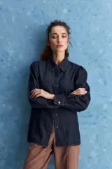Camisa de jean azul oscuro con calce relajado, cuello clásico, bolsillo aplicado en el delantero y mangas largas abullonadas con puños abotonados.