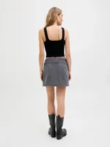 Minifalda gris de tiro medio, confeccionada en denim, con diseño de corte recto y presillas con cinturón ancho decorado con ojales metálicos y hebilla rectangular.