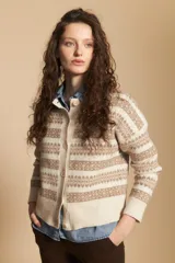 Cardigan corto de tejido jacquard con diseño geométrico en tonos beige y crema, con cierre frontal de botones y cuello redondo.