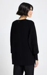 Cardigan negro de punto con escote en V y cierre frontal de botones. Presenta mangas tres cuartos y bolsillos frontales. El diseño destaca por sus bordados coloridos con motivos de cerezas y frases en francés distribuidas por toda la prenda.