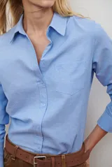 Camisa de corte recto confeccionada en tela Oxford, color azul claro. Presenta cuello clásico, cierre frontal con botones, mangas largas con puños abotonados y un bolsillo aplicado en el pecho.
