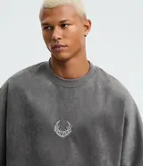 Remera oversized masculina de media malla con toque gamuza, color gris oscuro con efecto lavado. Presenta un bordado blanco en forma de media luna en el pecho y un estampado lettering en la parte delantera y trasera.